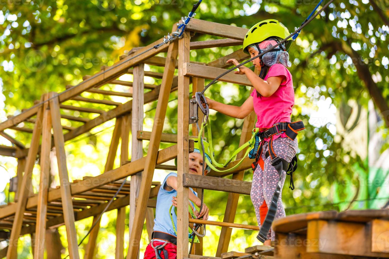 adventure climbing high wire park - children on course rope park in mountain helmet and safety equipment photo
