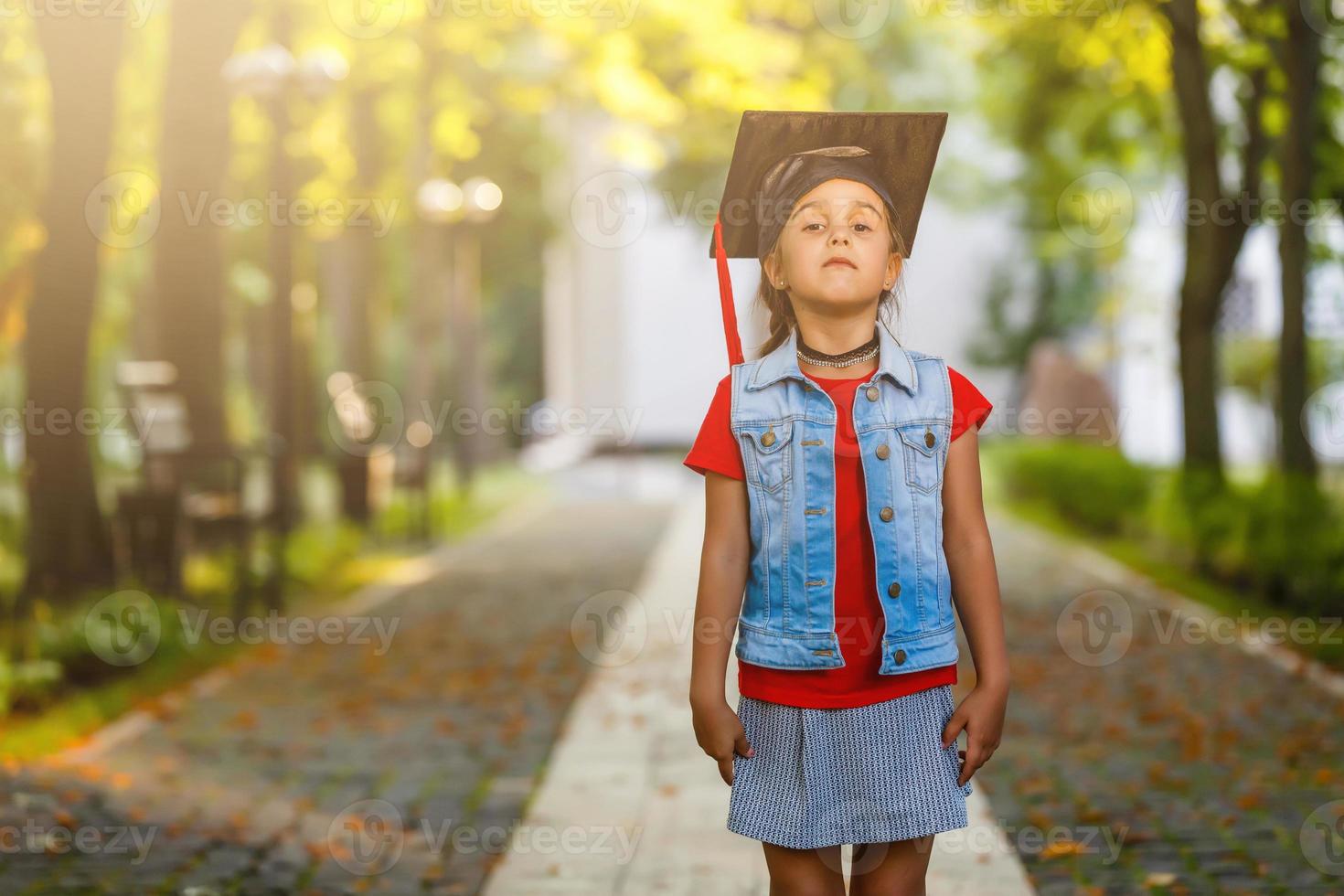 Happy school kid graduate in graduation cap looking up photo