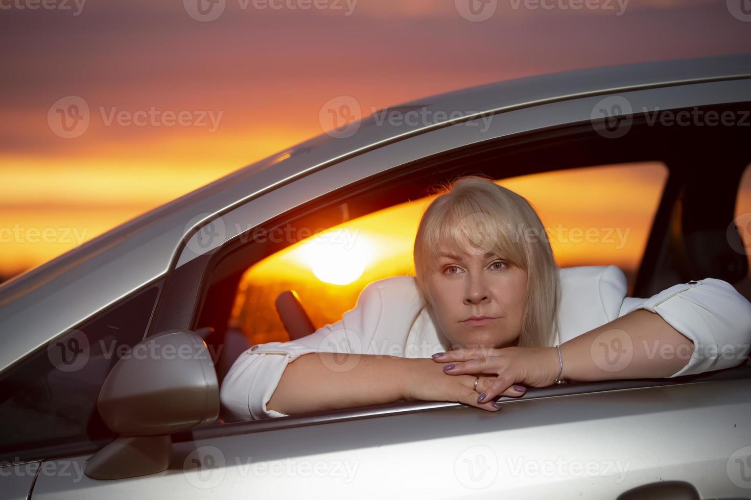 triste mujer de mediana edad conduciendo un coche. retrato psicológico de una mujer exitosa pero triste. ella piensa en su vida. foto