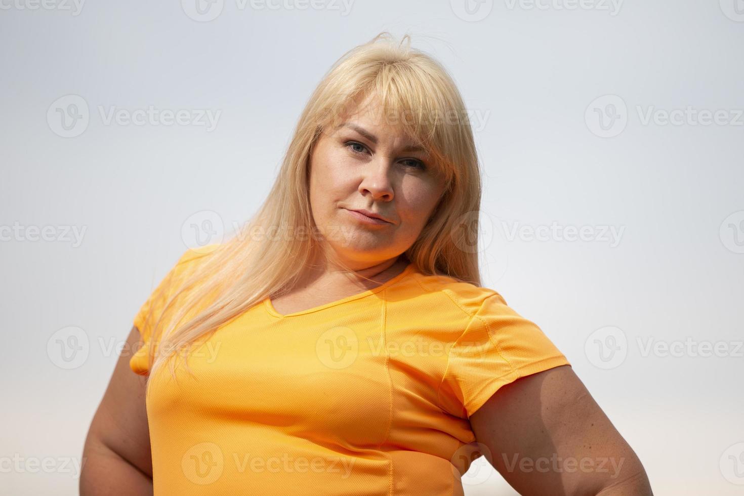 retrato de una mujer europea de mediana edad en chándal, posando para la cámara, relajándose. emocionada mujer con sobrepeso en chándal de moda descansando después de hacer ejercicio. foto