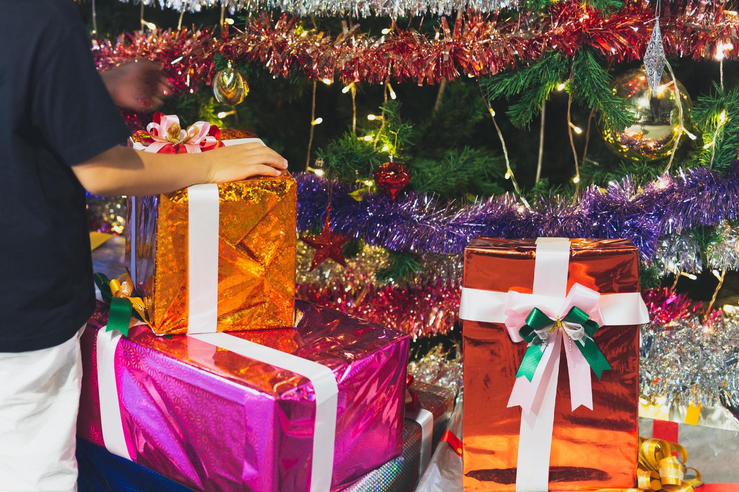 Hand of children on christmas presents and gift boxes under Christmas tree photo