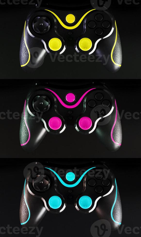 Three gaming joysticks, on yellow-cyan-Magenta and black background. photo