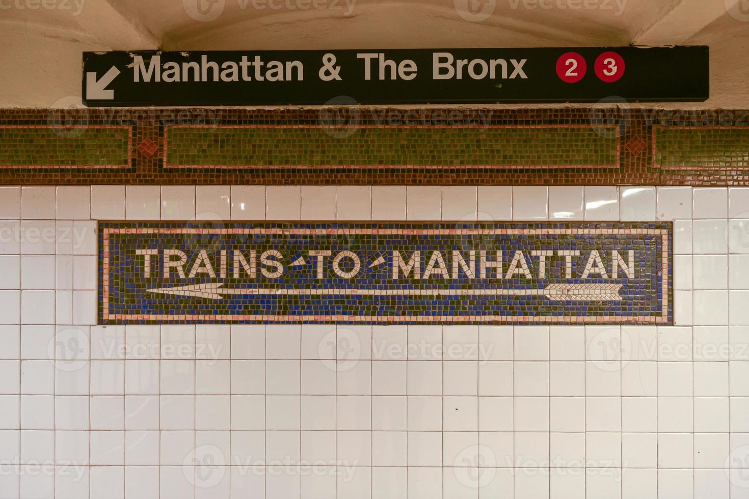 trenes a la señal de flecha de mosaico de manhattan en el metro de nyc. foto