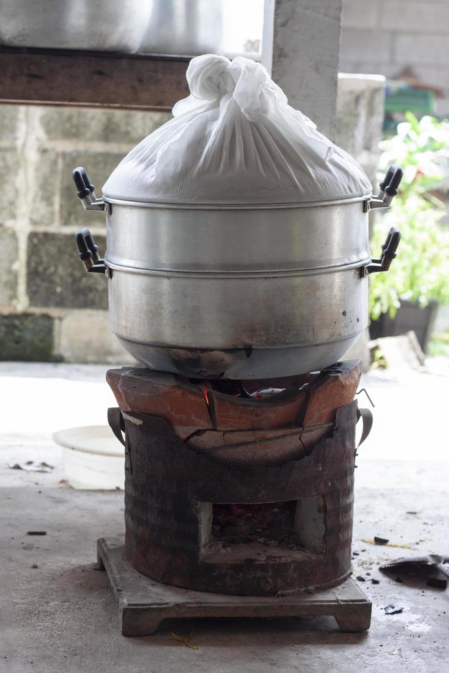 el vapor está cocinando comida al vapor en la estufa de carbón en la cocina rural. foto