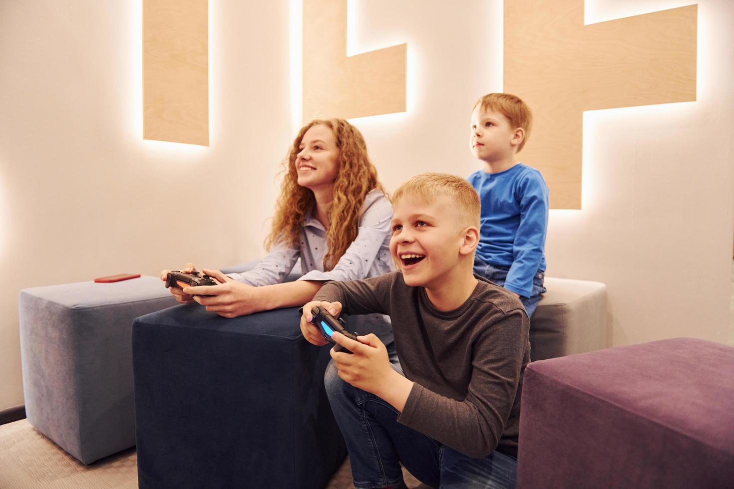 Cheerful kids sitting indoors and playing video games together photo