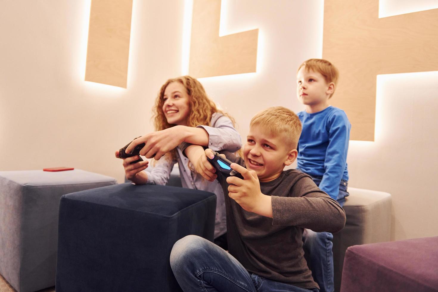 niños alegres sentados adentro y jugando videojuegos juntos foto
