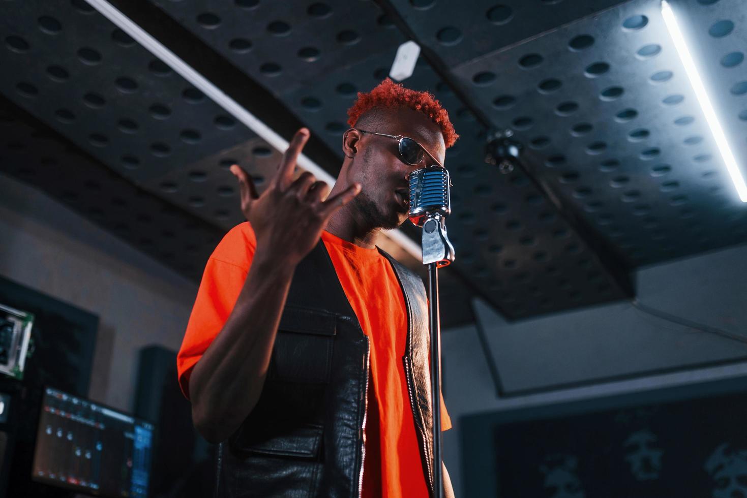 Having vocal practice. Young african american performer rehearsing in a recording studio photo