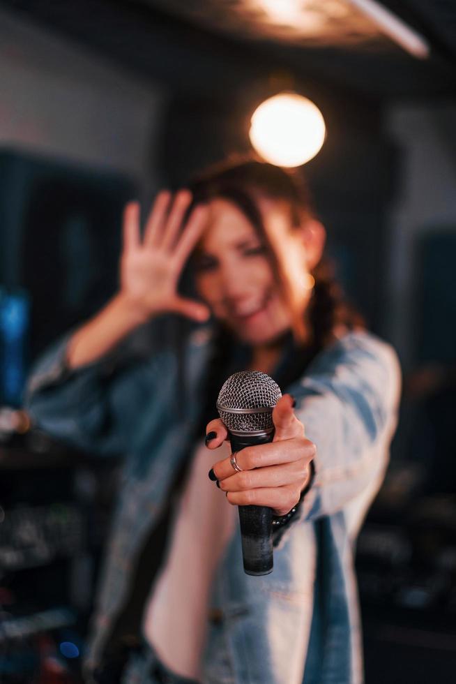 vista de cerca del micrófono. joven y bella intérprete femenina ensayando en un estudio de grabación foto