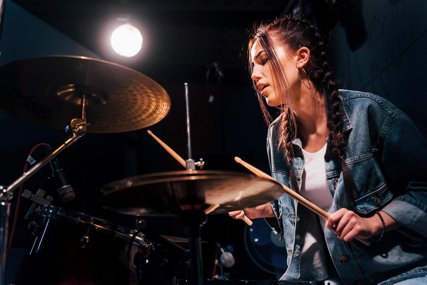 Plays drums. Young beautiful female performer rehearsing in a recording studio photo