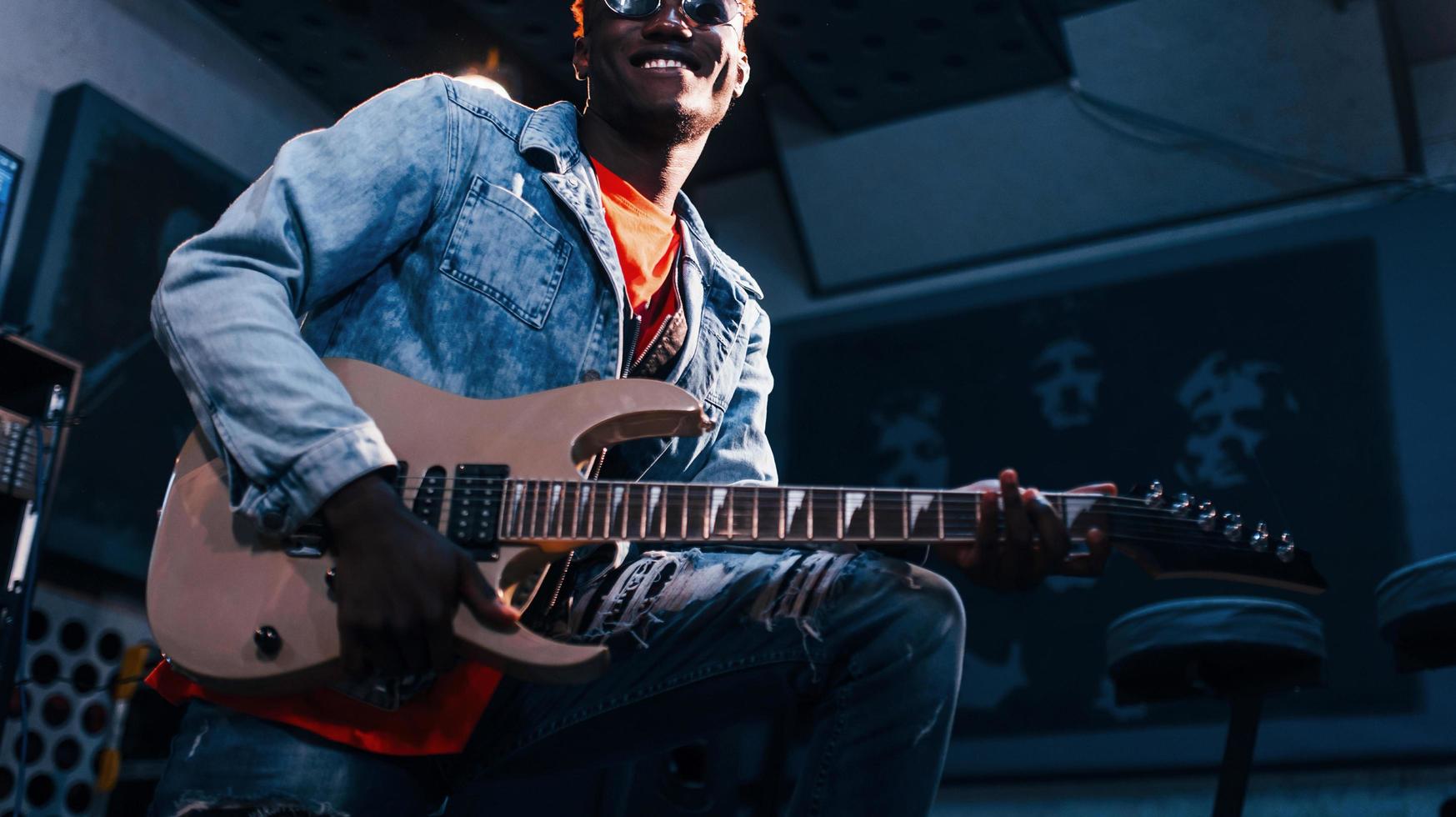 Plays guitar. Young african american performer rehearsing in a recording studio photo