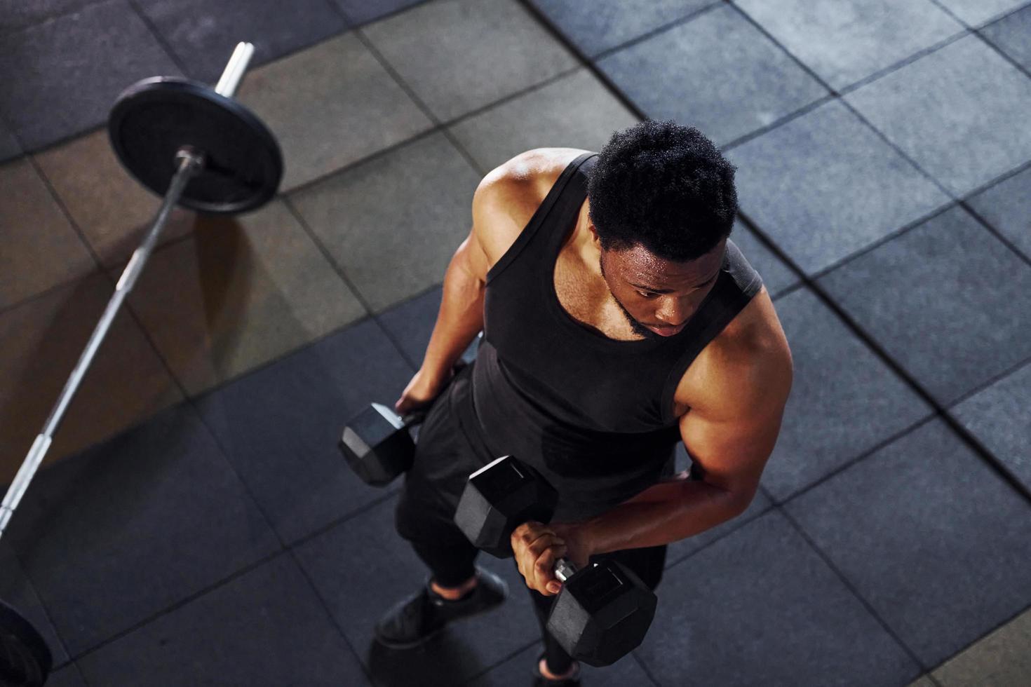 Strong african american man in sportive clothes have workout day in the gym photo