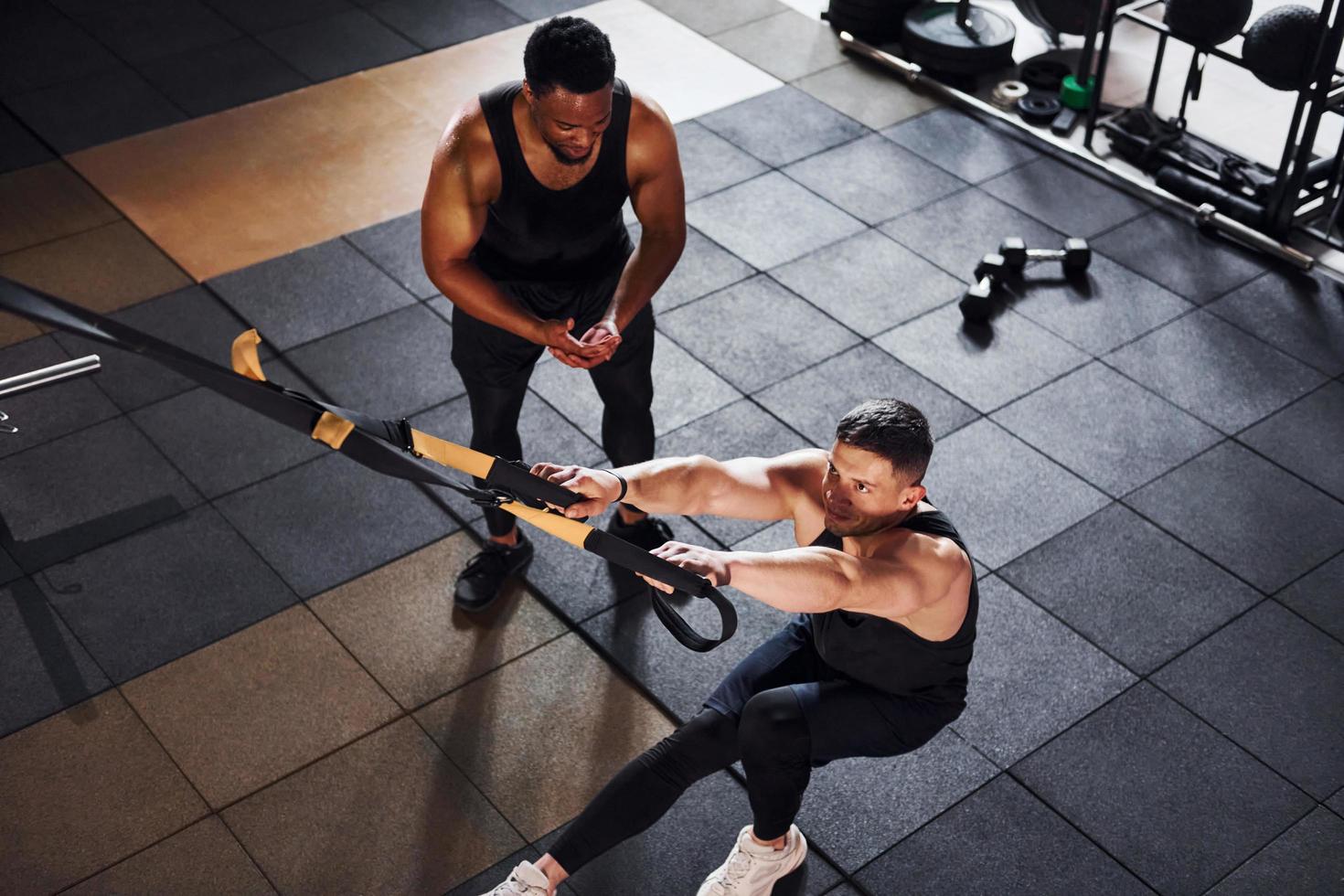 Personal trainer is on job. African american man with white guy have workout day in gym photo