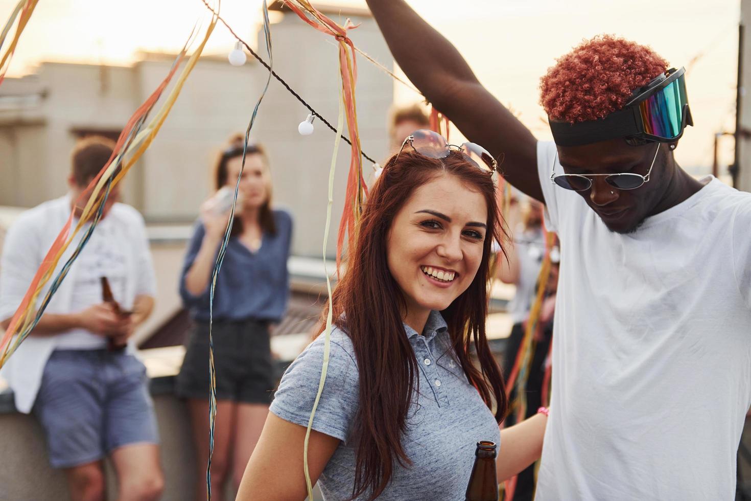 Posing for a camera. Group of young people in casual clothes have a party at rooftop together at daytime photo