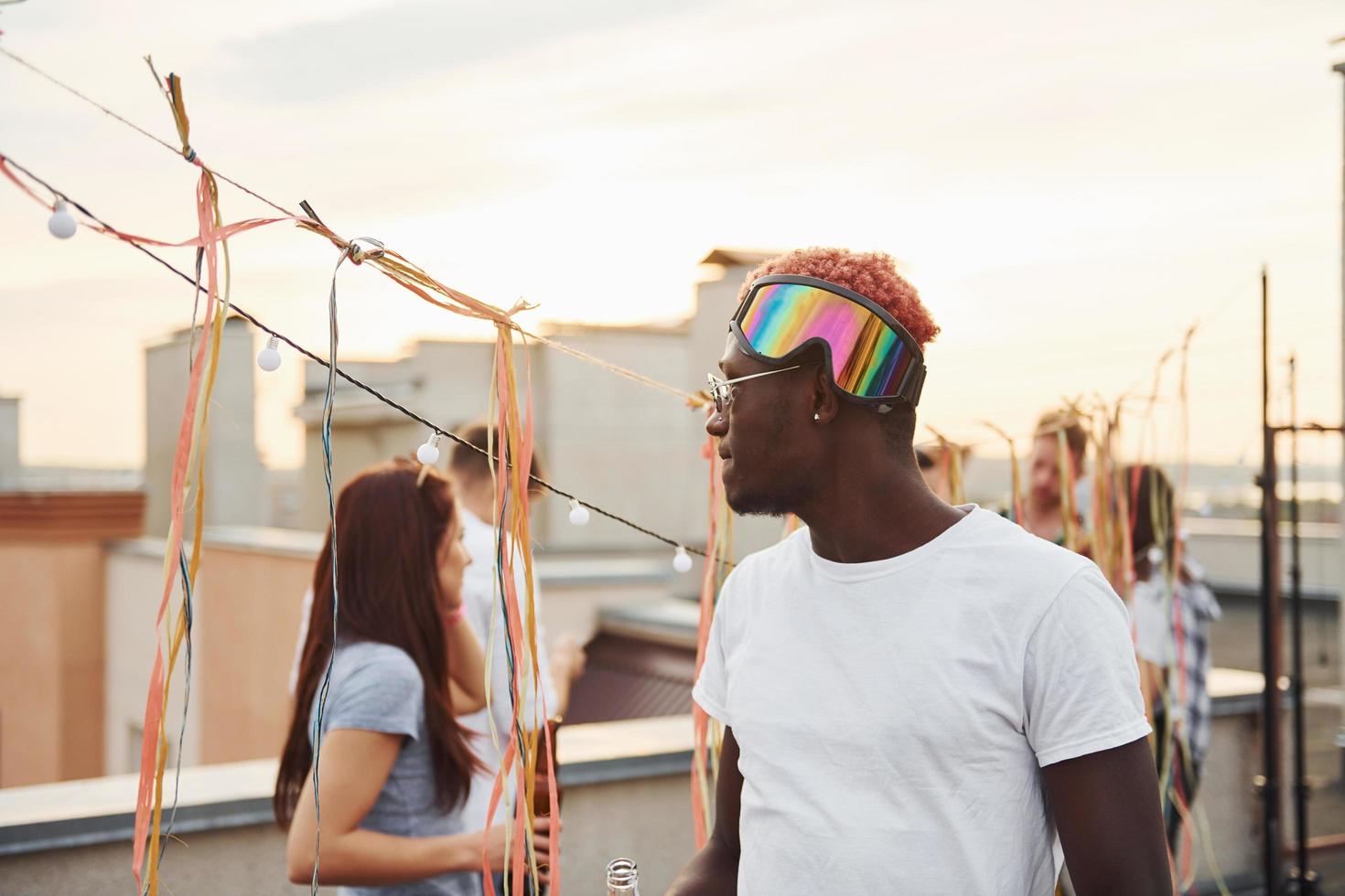 Posing for a camera. Group of young people in casual clothes have a party at rooftop together at daytime photo