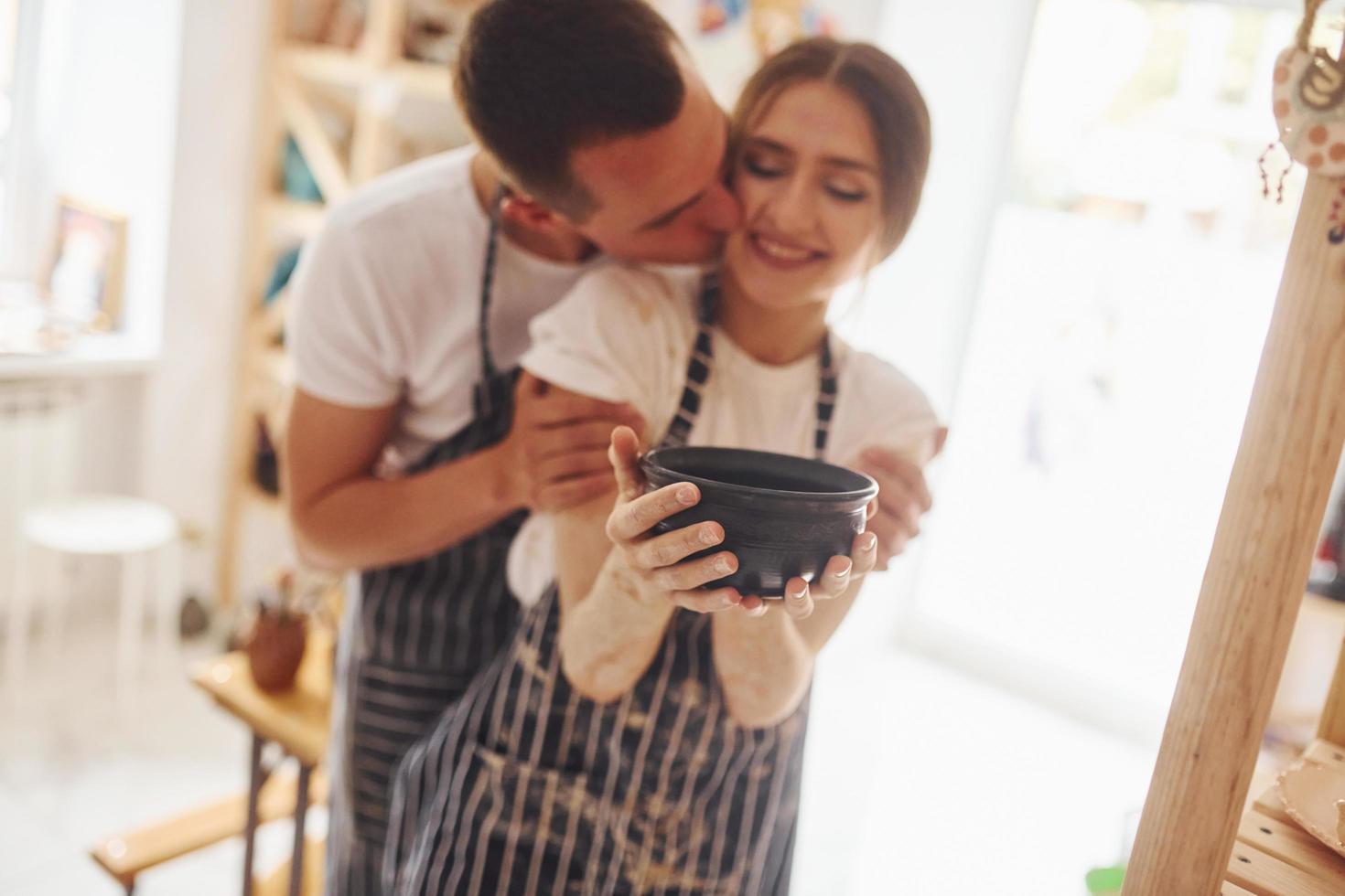 Job is done. With her boyfriend or husband. Young female ceramist indoors with finished handmade clay product. Conception of pottery photo