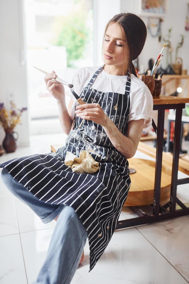 Young female ceramist indoors with handmade clay product. Conception of pottery photo