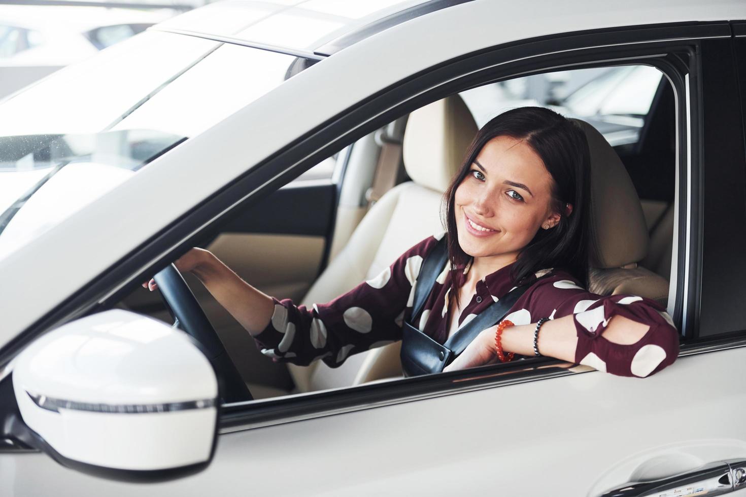 Side view of beautiful young brunette that inside of modern automobile. Riding car photo