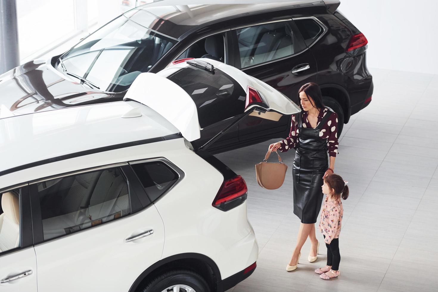 Mother with her daughter walking together near modern automobile indoors photo