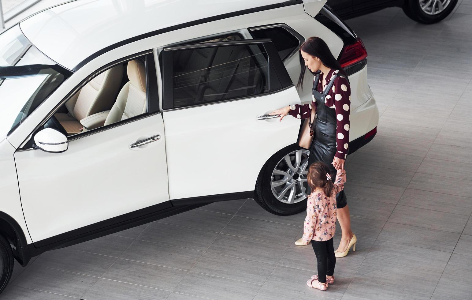 Mother with her daughter walking together near modern automobile indoors photo