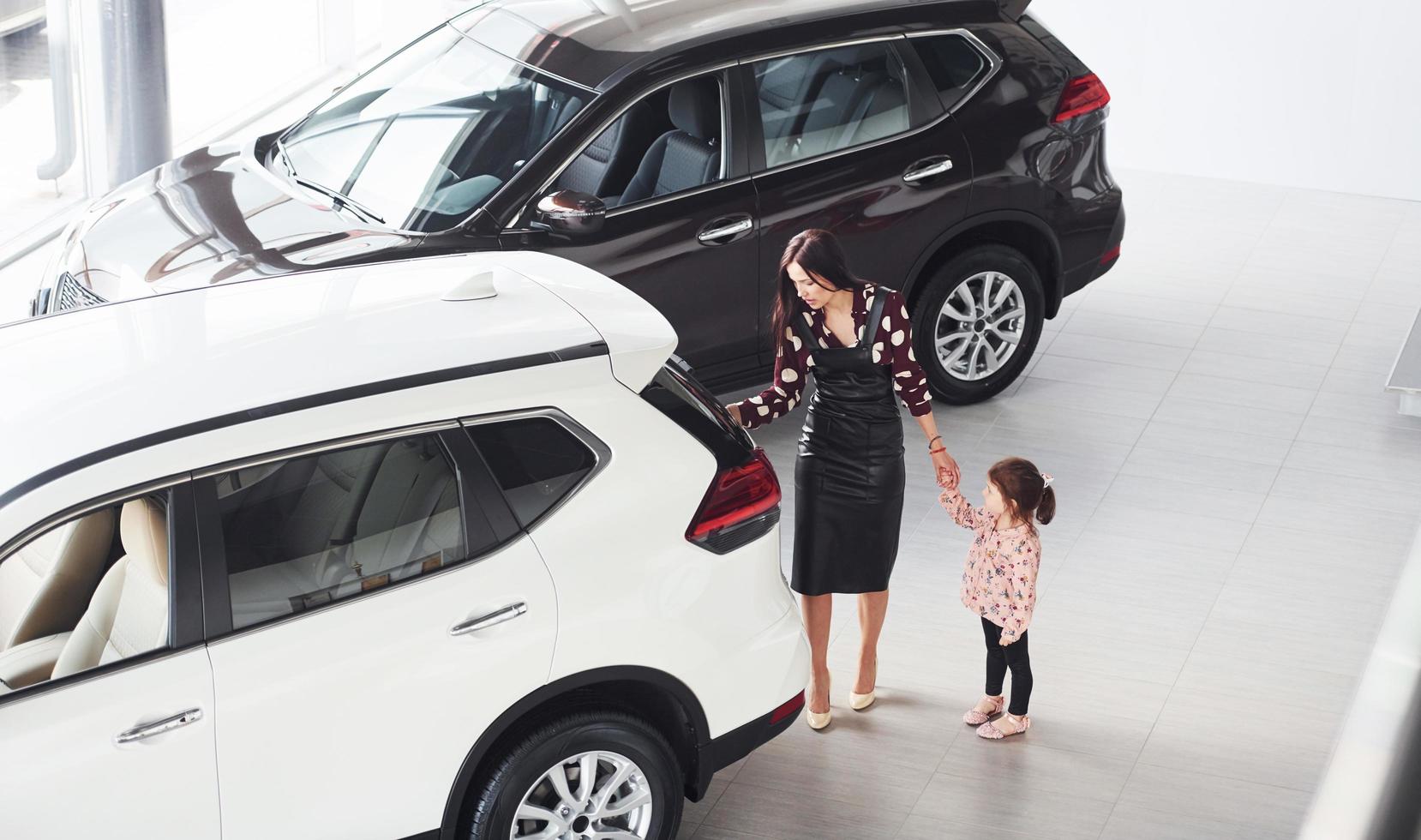 Mother with her daughter walking together near modern automobile indoors photo