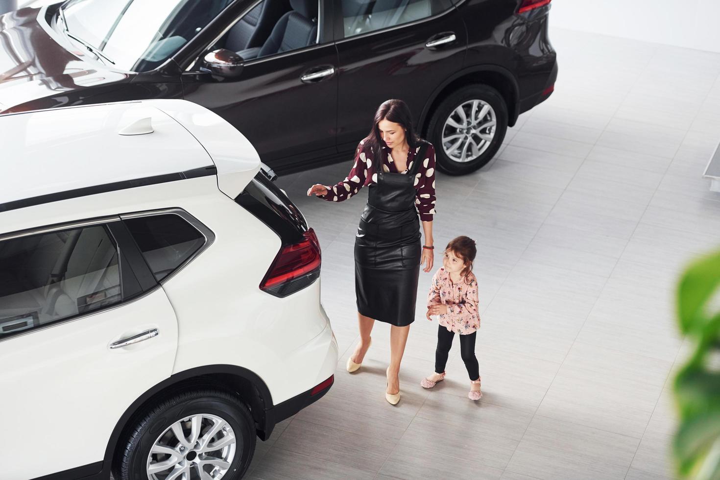 Mother with her daughter walking together near modern automobile indoors photo