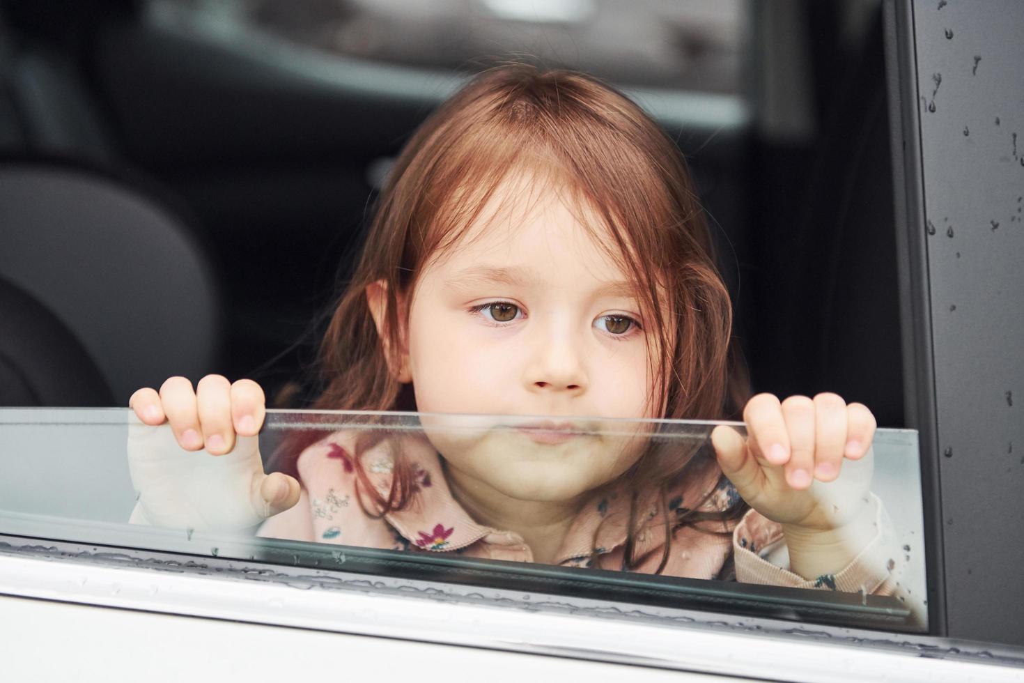 linda niña mira a través del coche de la ventana. concepción de viajar y vacaciones foto