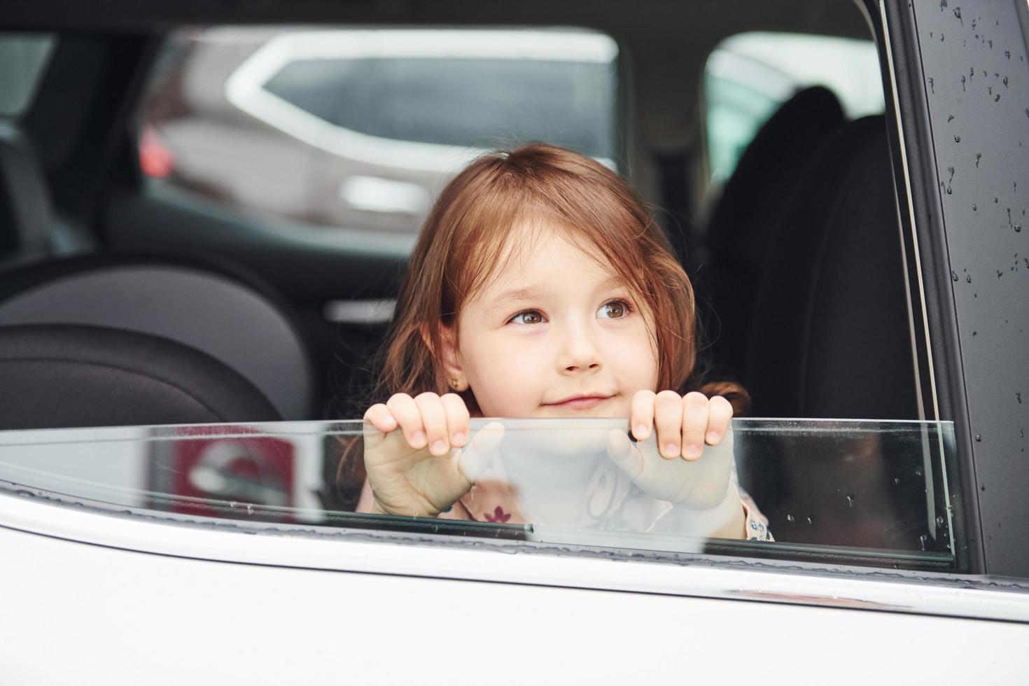 linda niña mira a través del coche de la ventana. concepción de viajar y vacaciones foto