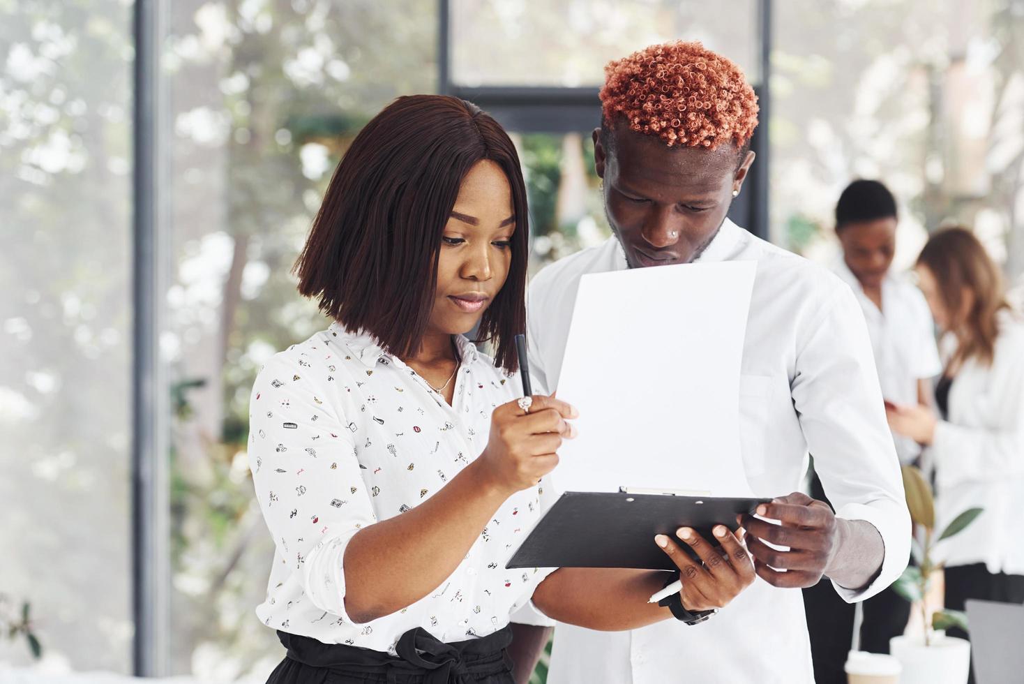 Holding notepad. Group of african american business people working in office together photo