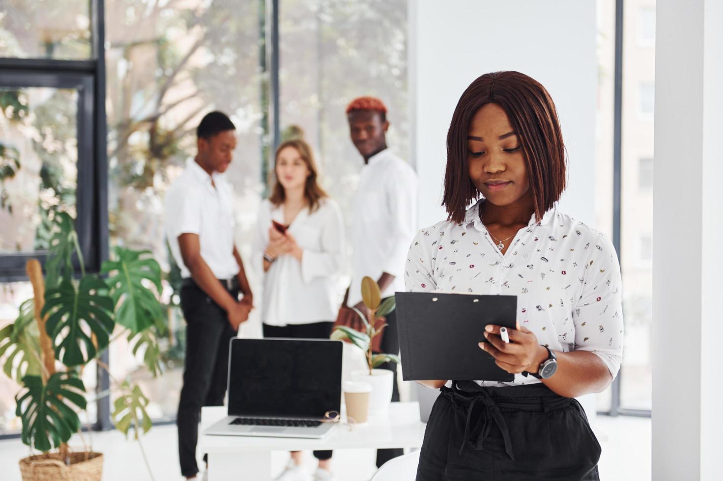 Woman holding notepad. Group of african american business people working in office together photo