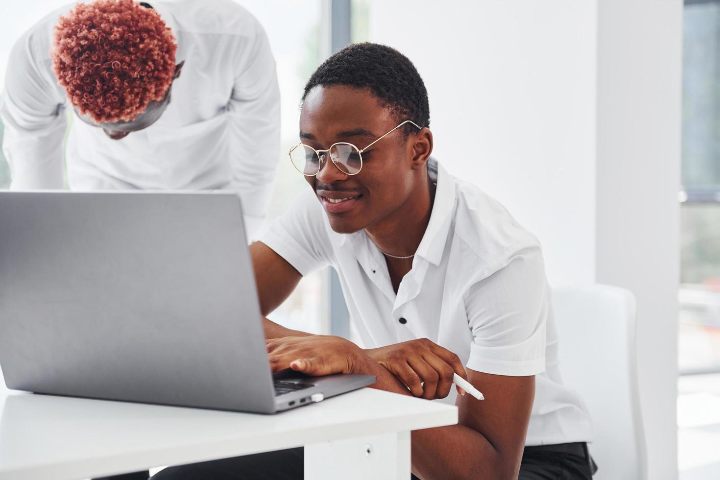 sentado con la computadora portátil. grupo de empresarios afroamericanos que trabajan juntos en la oficina foto