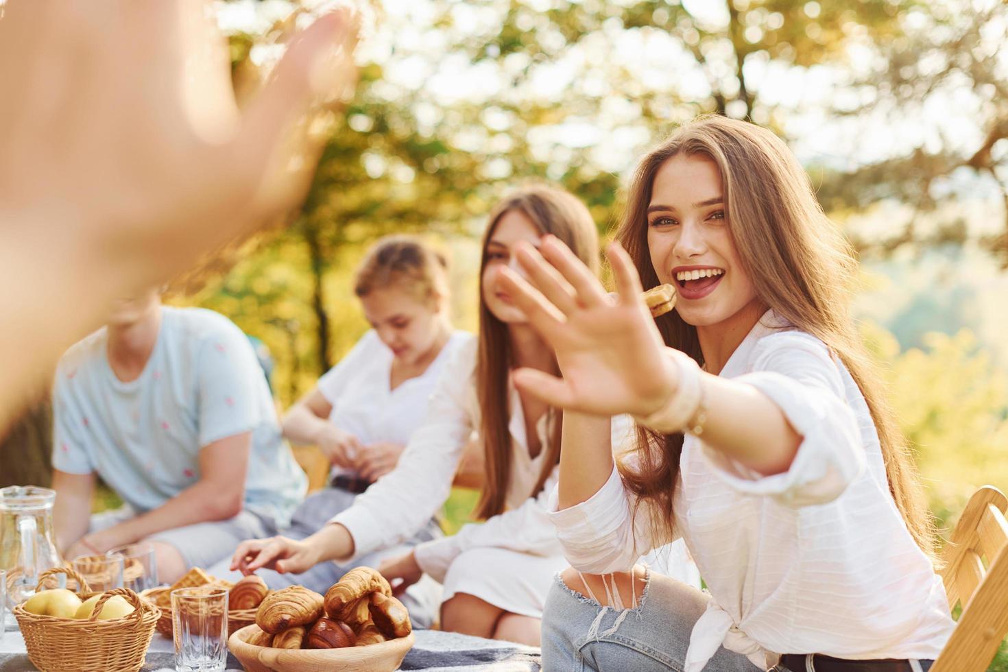 mujer chocando los cinco con el fotógrafo. grupo de jóvenes tienen vacaciones al aire libre en el bosque. concepción de fin de semana y amistad foto