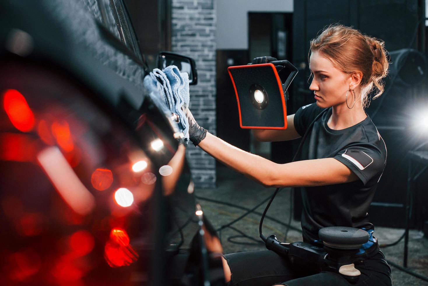 Final polishing. Modern black automobile get cleaned by woman inside of