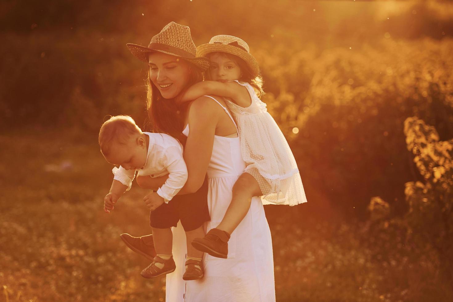 familia feliz de madre, hijo pequeño e hija que pasan tiempo libre en el campo en el día soleado del verano foto