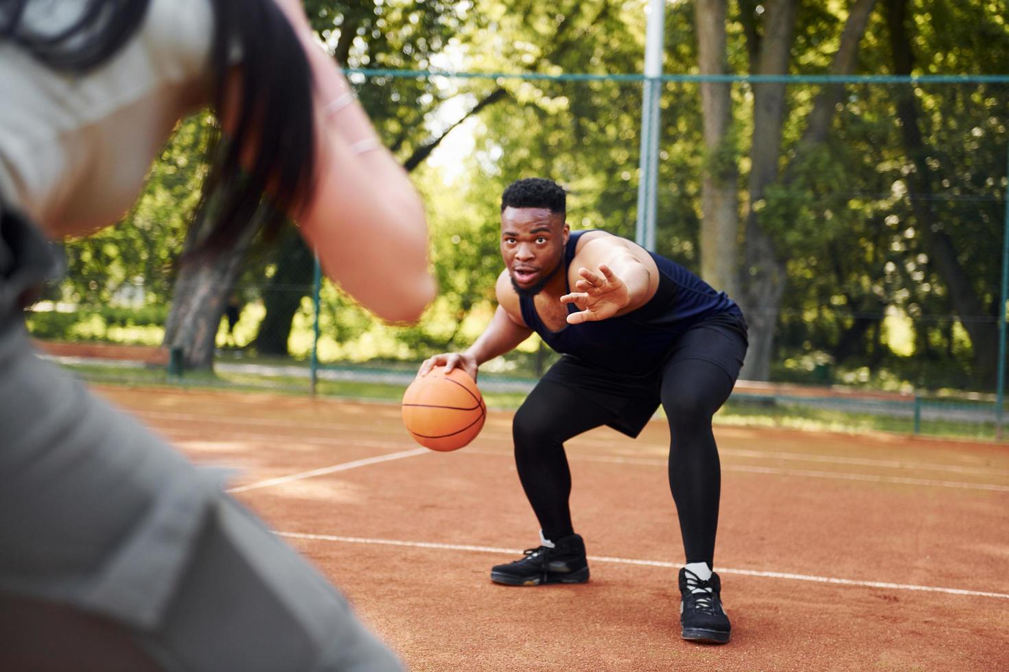 African american man with girl plays basketball on the court outdoors photo