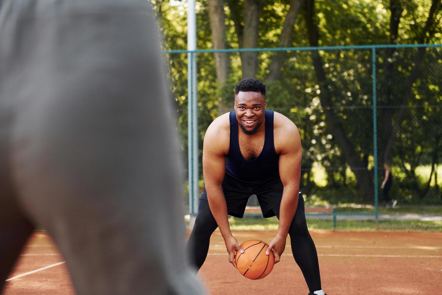 African american man with girl plays basketball on the court outdoors photo