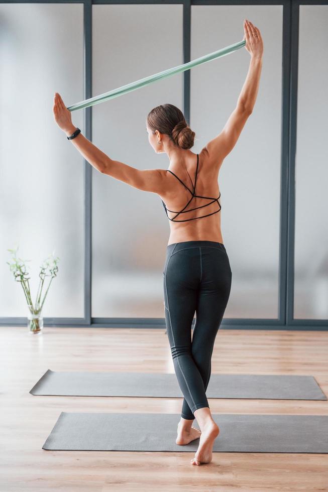 Rear view. Young woman in sportive wear and with slim body have fitness yoga day indoors photo