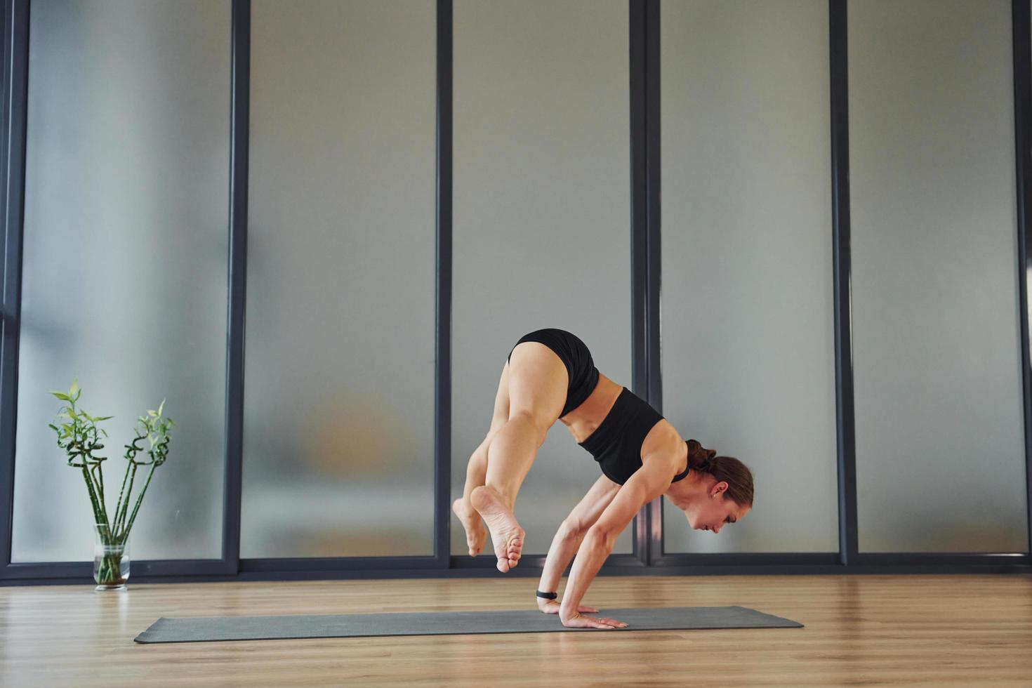 Difficult exercise. Young woman in sportive wear and with slim body have fitness yoga day indoors photo