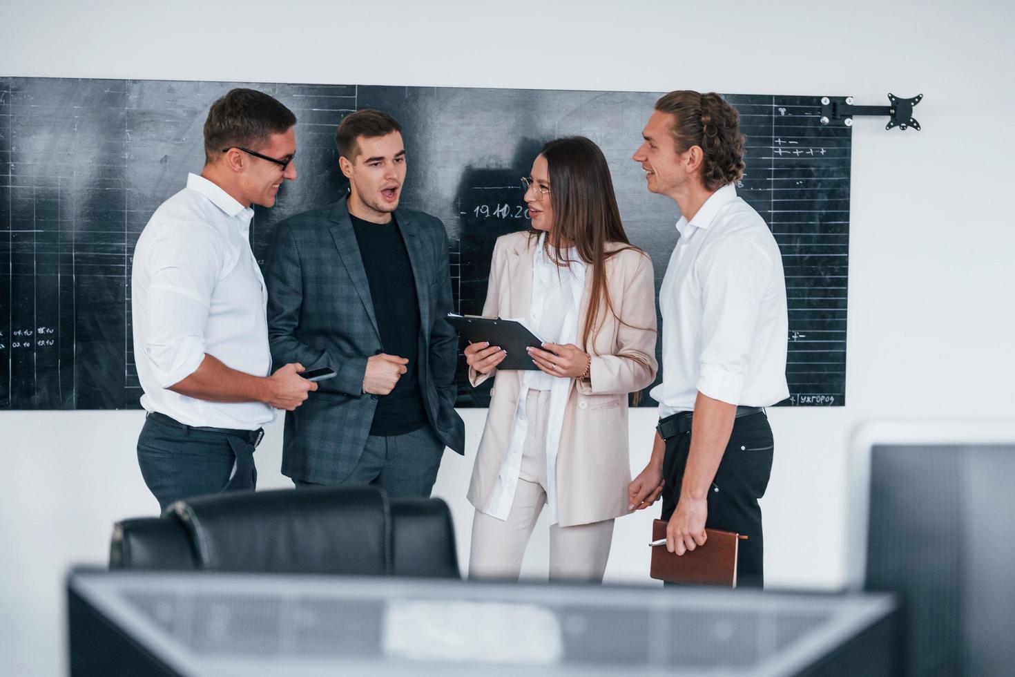 Team of stockbrokers works in modern office near blackboard photo