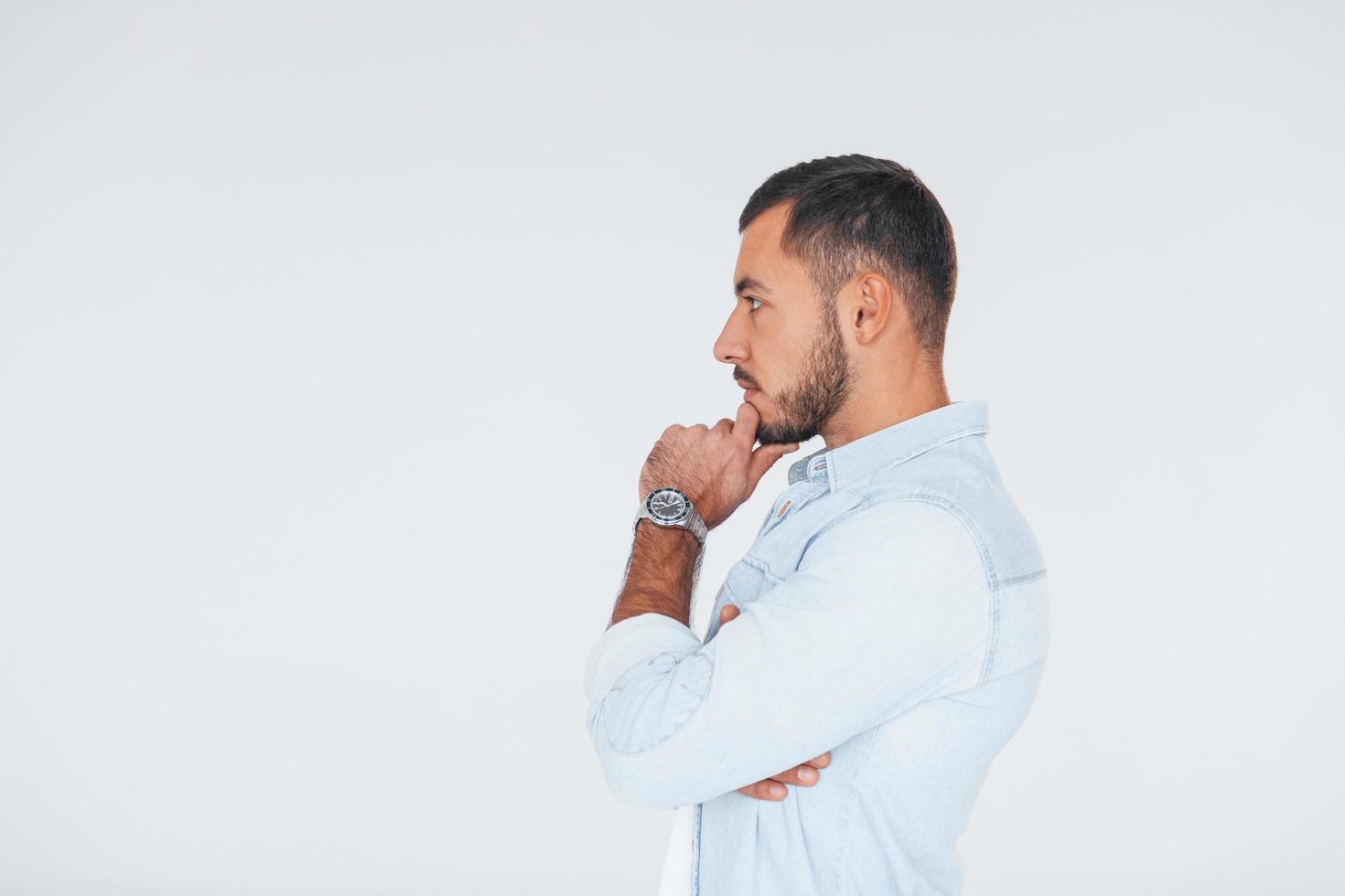 Side view. Young handsome man standing indoors against white background photo