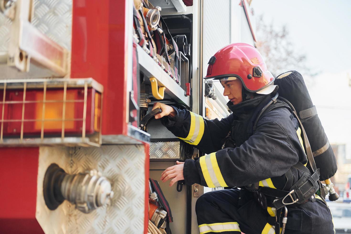 Takes equipment. Female firefighter in protective uniform standing near truck photo