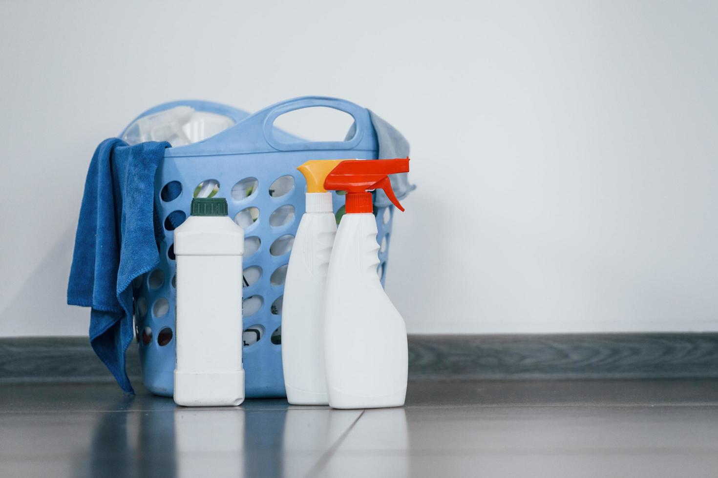 Close up view of bottles with detergent and basket indoors on the floor photo