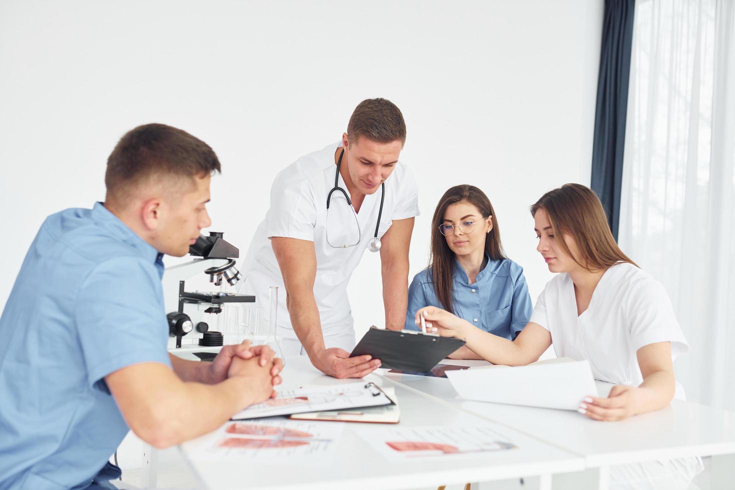 hombre con microscopio. grupo de médicos jóvenes está trabajando juntos en la oficina moderna foto