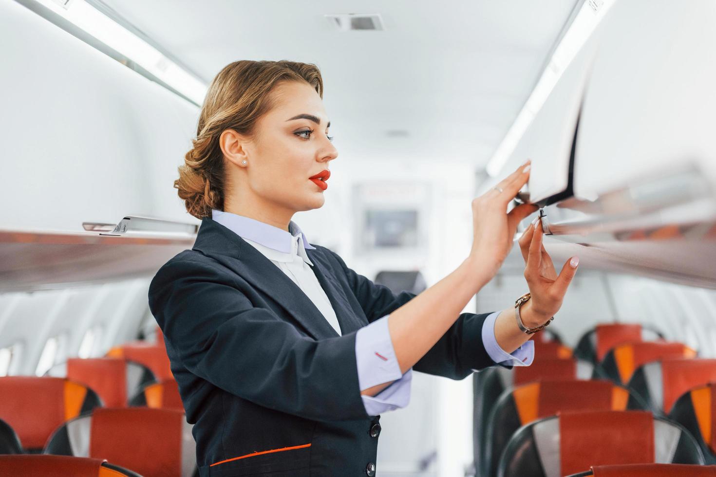 Asientos vacíos. joven azafata en el trabajo en el avión de pasajeros foto