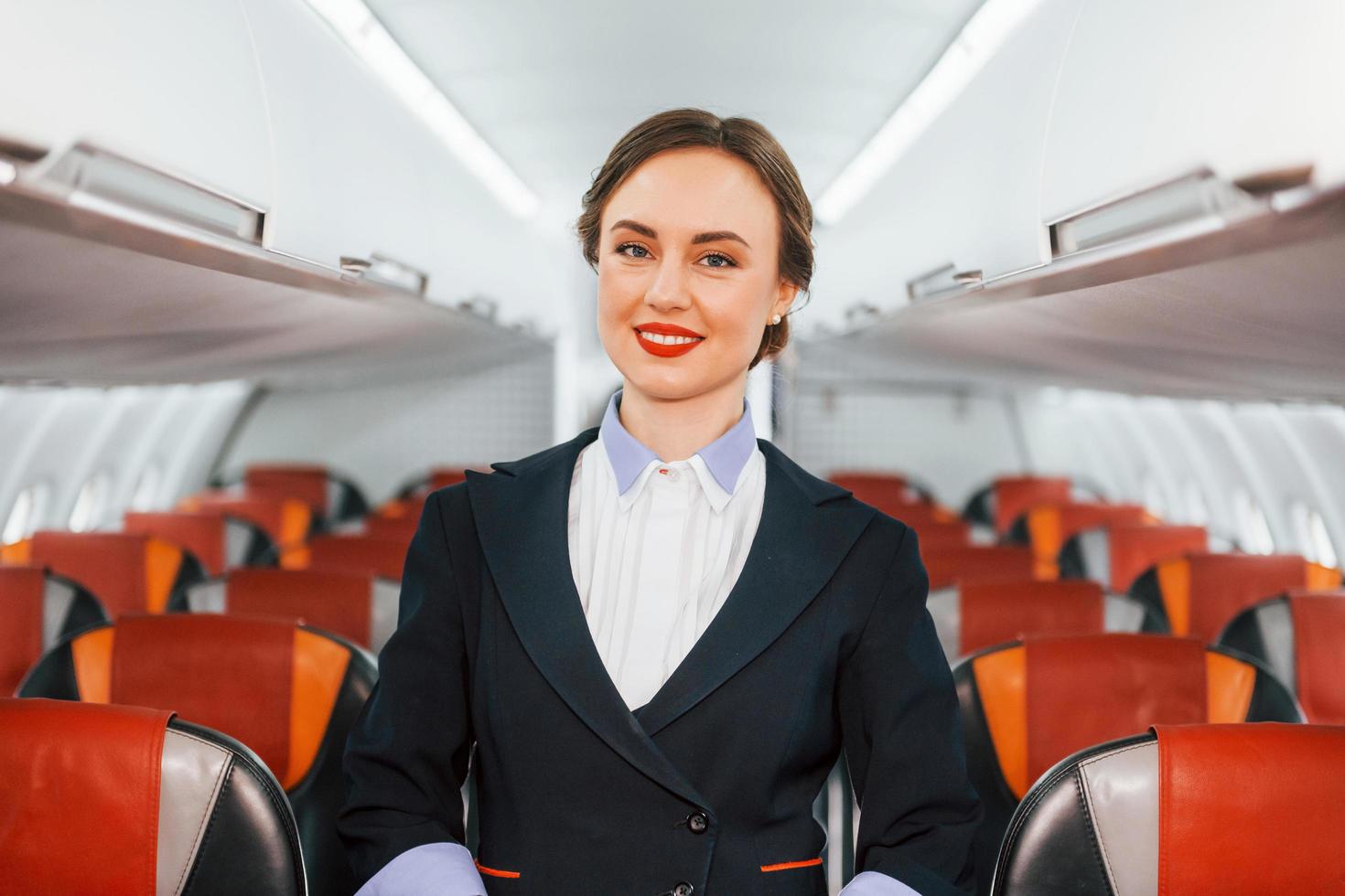 Asientos vacíos. joven azafata en el trabajo en el avión de pasajeros foto