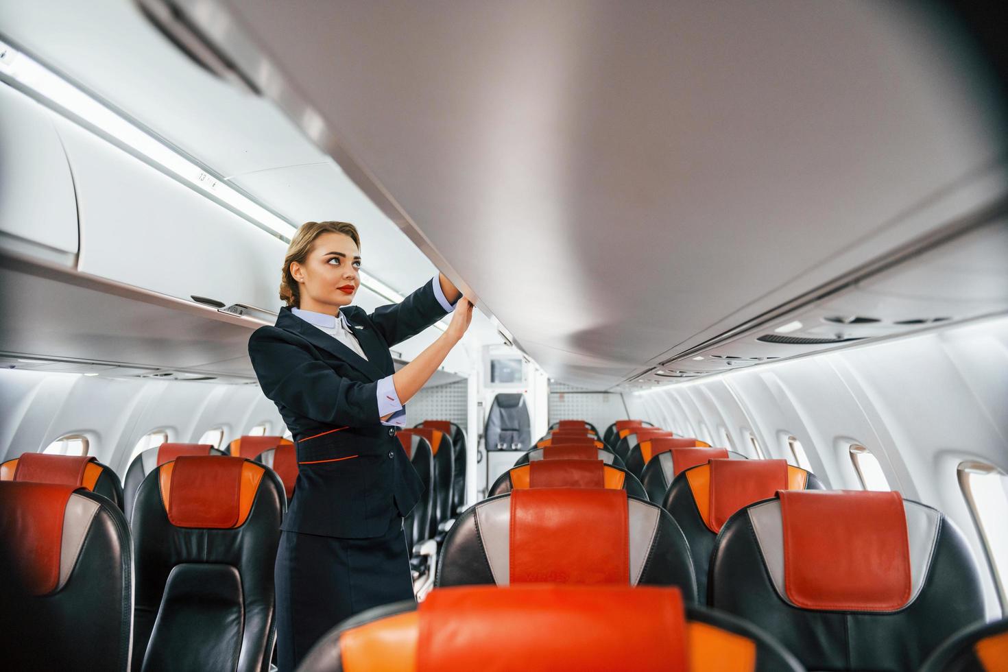 Asientos vacíos. joven azafata en el trabajo en el avión de pasajeros foto