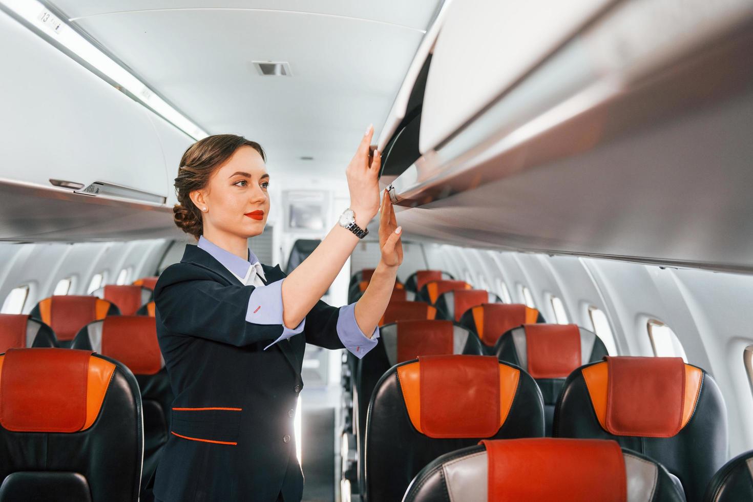 Asientos vacíos. joven azafata en el trabajo en el avión de pasajeros foto