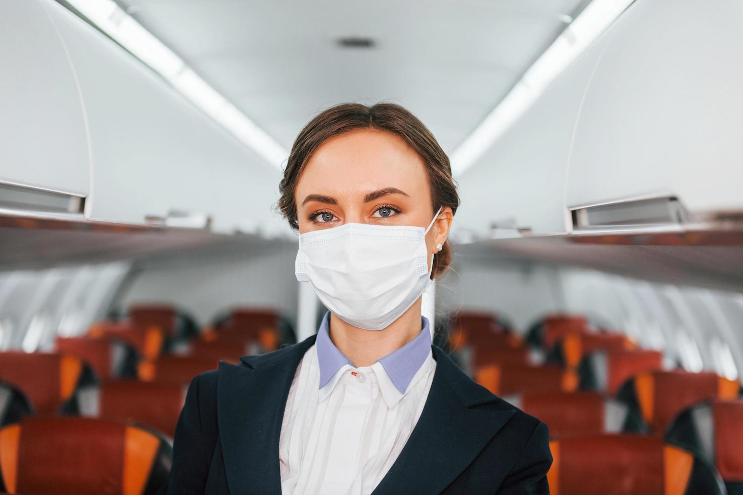 en máscara joven azafata en el trabajo en el avión de pasajeros foto