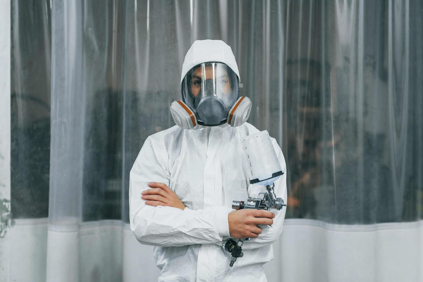 en uniforme blanco protector. el hombre está trabajando en el servicio de automóviles foto