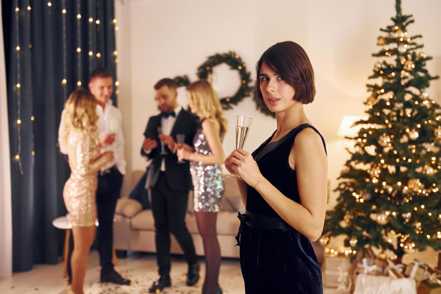 Standing near christmas tree. Group of people have a new year party indoors together photo