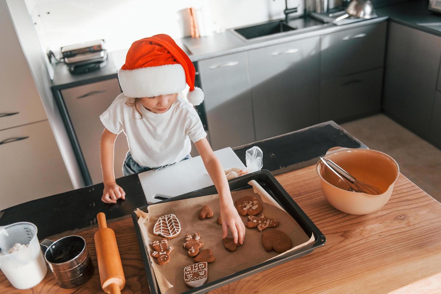 Little girl preparing Christmas cookies on the kitchen photo